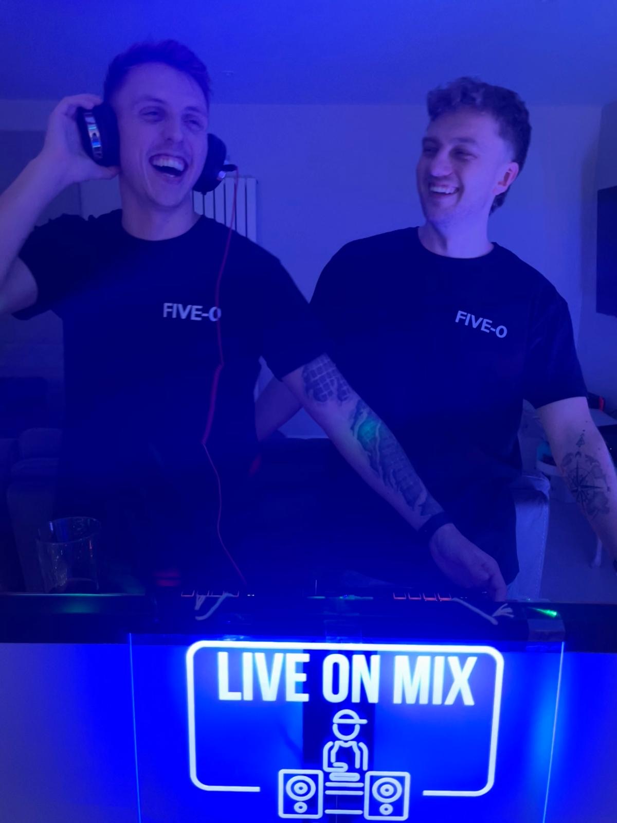 Five-O DJs laughing during performance with blue lighting